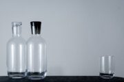 Kvetna 1794 Vial Glasflaschen und Wassergläser auf dunklem Tisch